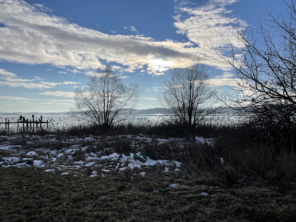 ein Feld mit Schnee auf dem Boden und ein Gewässer in der Ferne