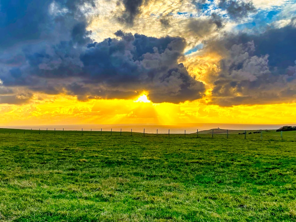 the sun is setting over a grassy field