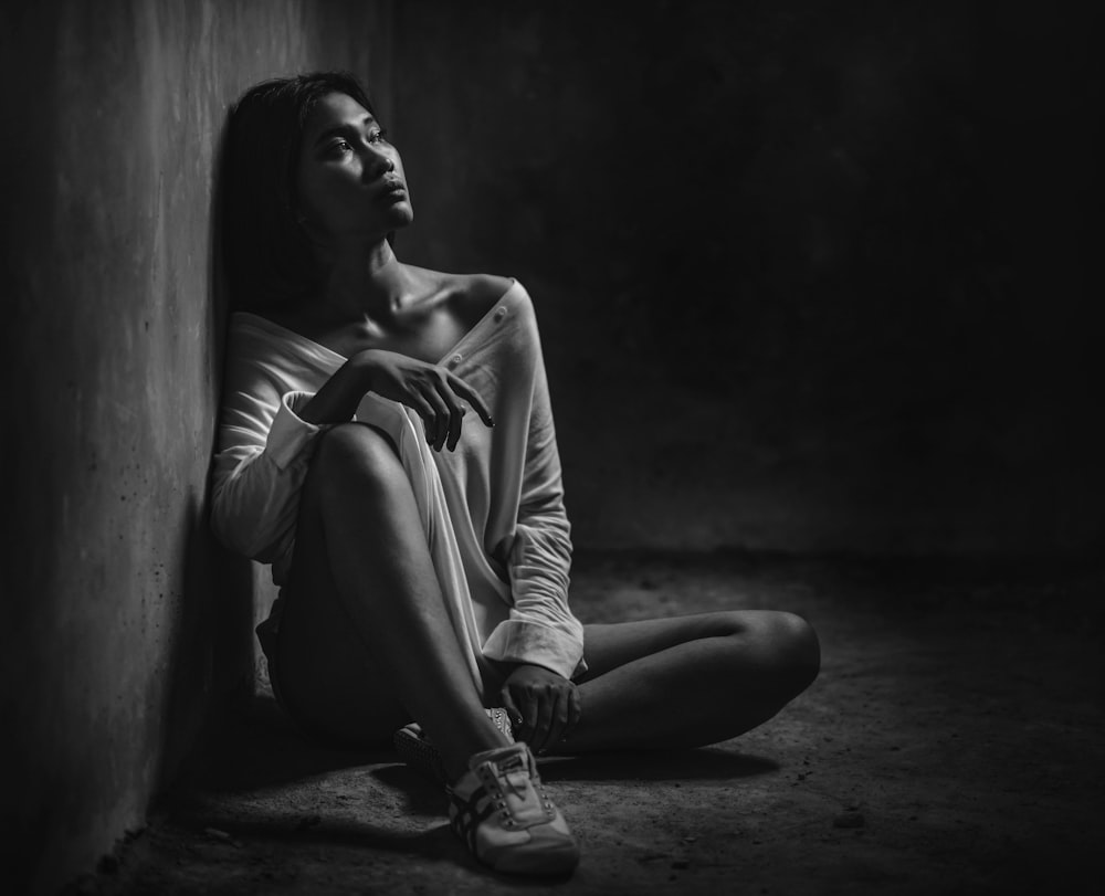 a black and white photo of a woman sitting on the floor