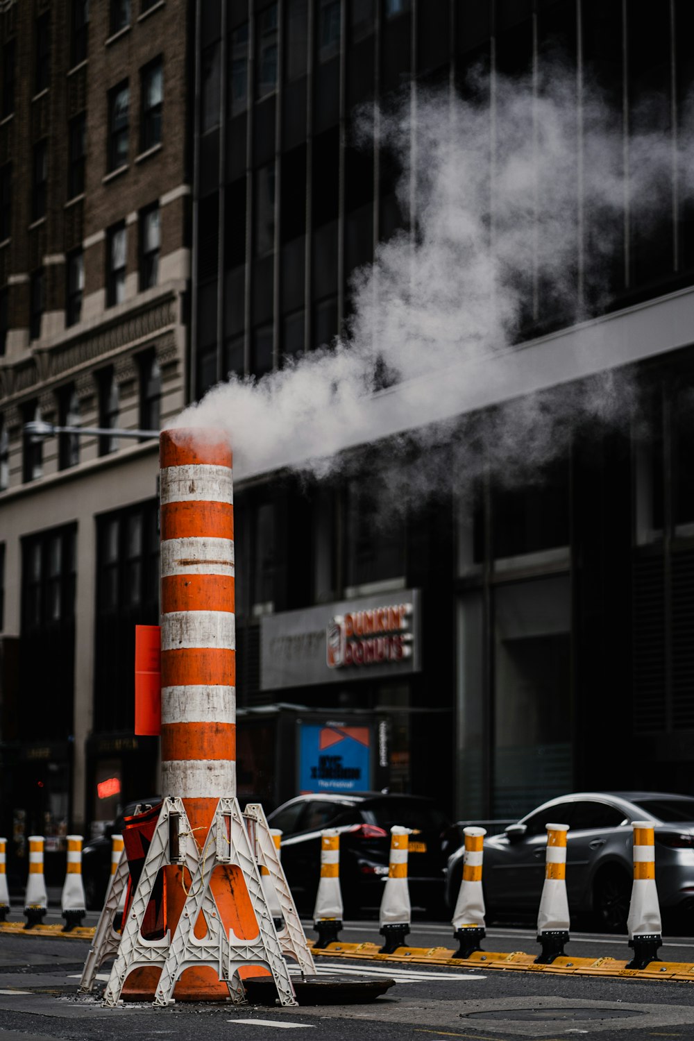 an orange and white cone sitting on the side of a road