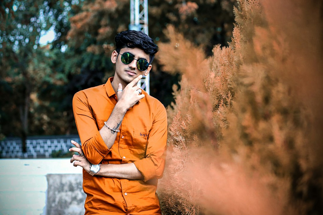 a man in an orange shirt is holding a cell phone,