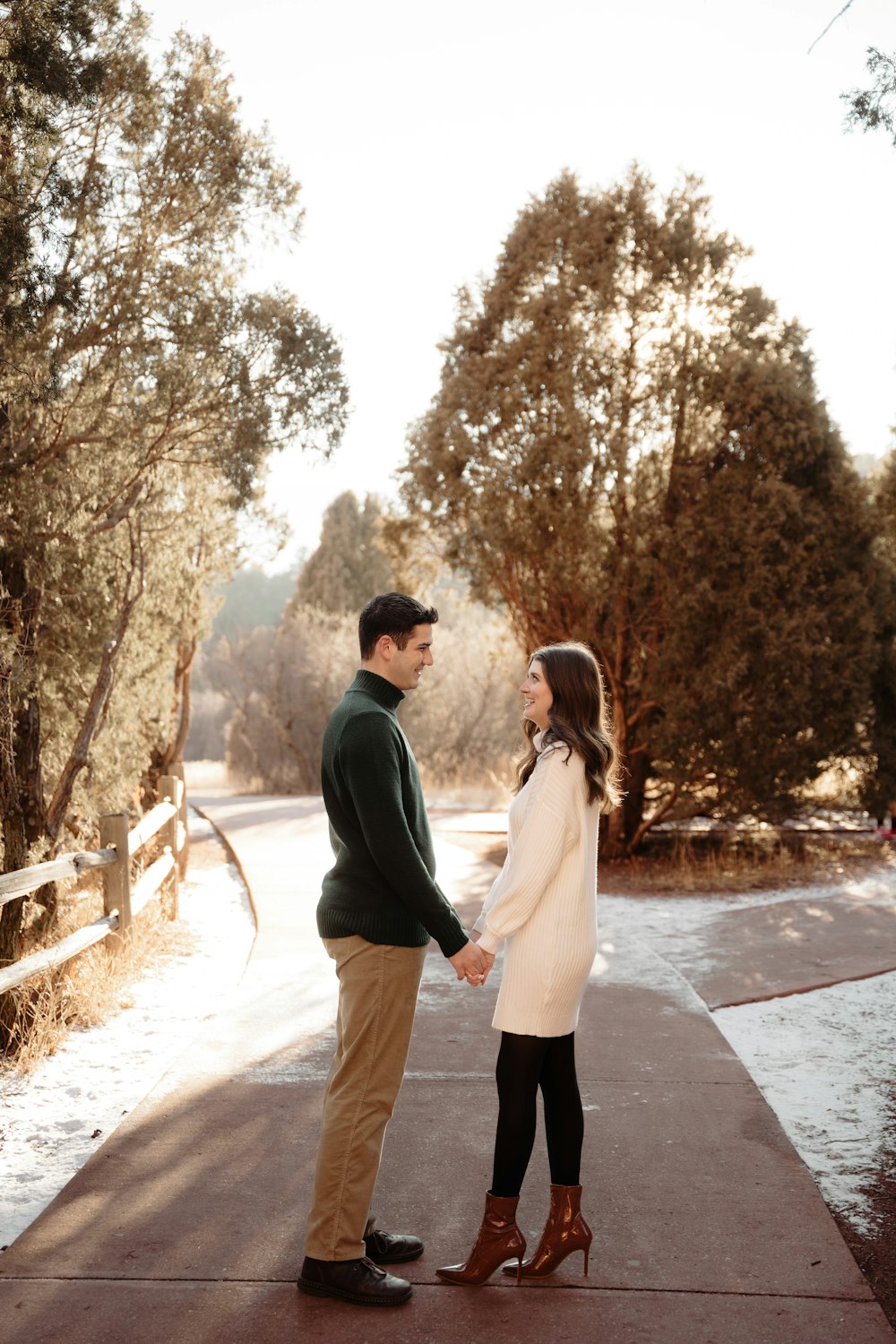 a man and woman holding hands while standing on a sidewalk