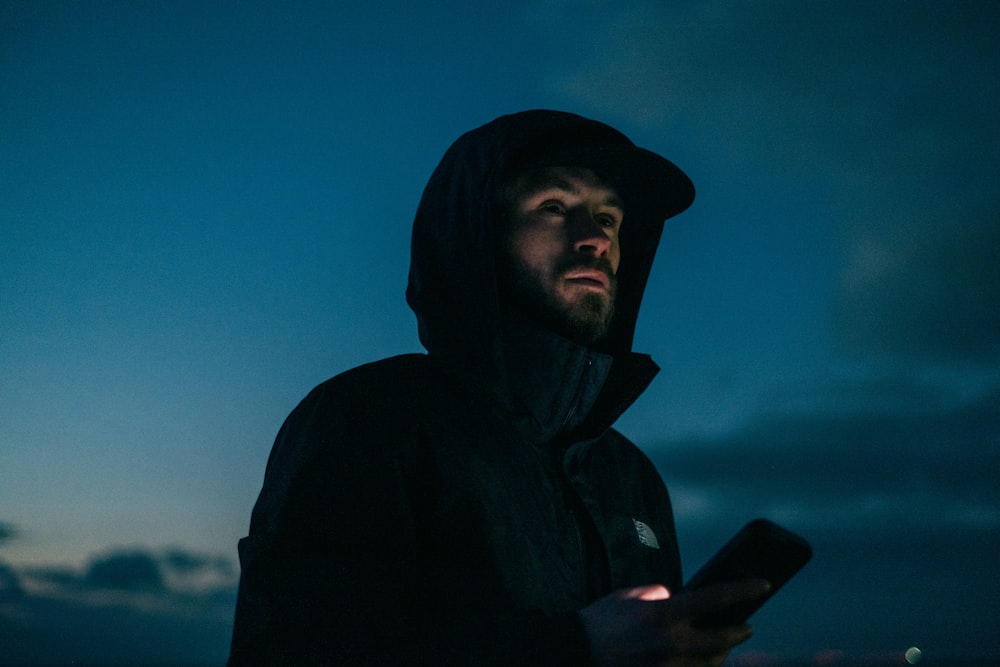 a man in a hooded jacket holding a cell phone