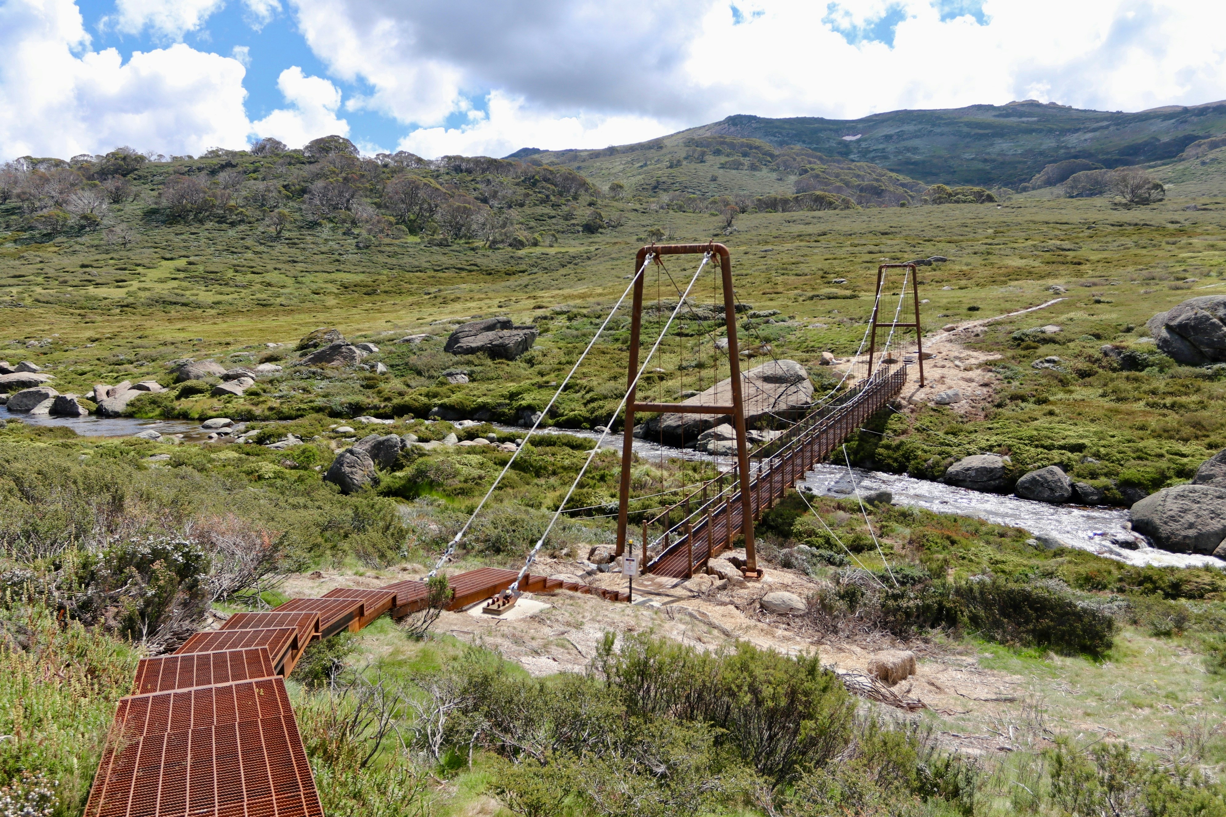 eine rostige Brücke über einen Bach mitten auf einem Feld