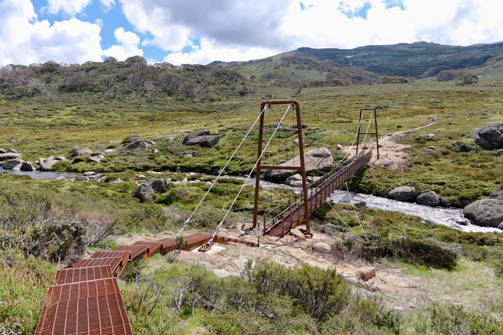 a rusty bridge over a stream in the middle of a field