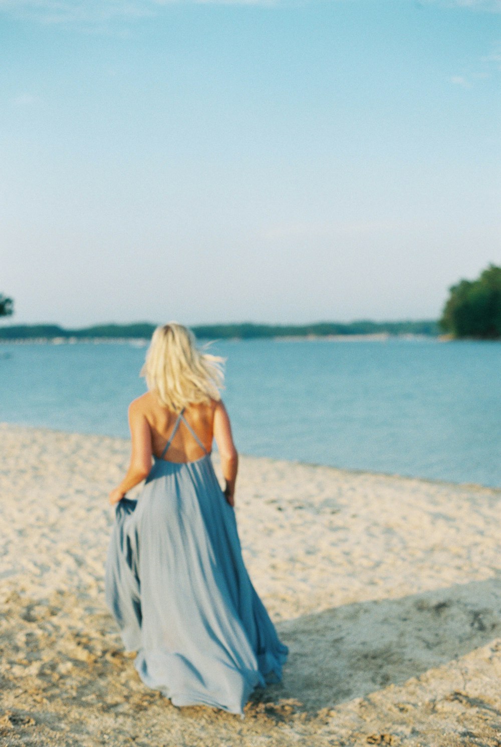 a woman in a blue dress walking on a beach
