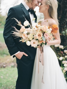 a bride and groom standing in front of a tree