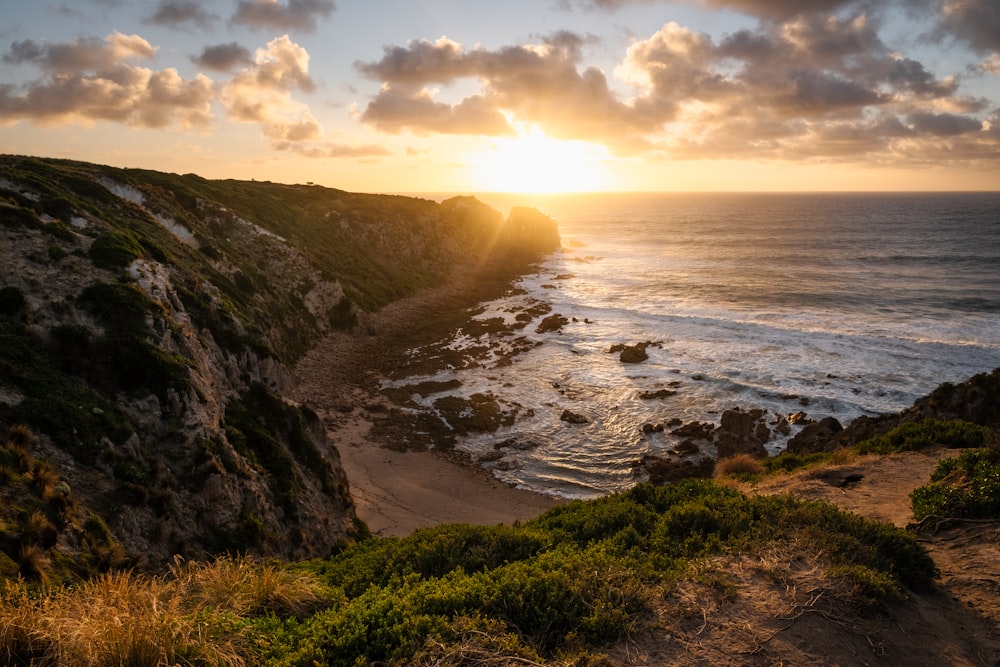 the sun is setting over the ocean on the coast