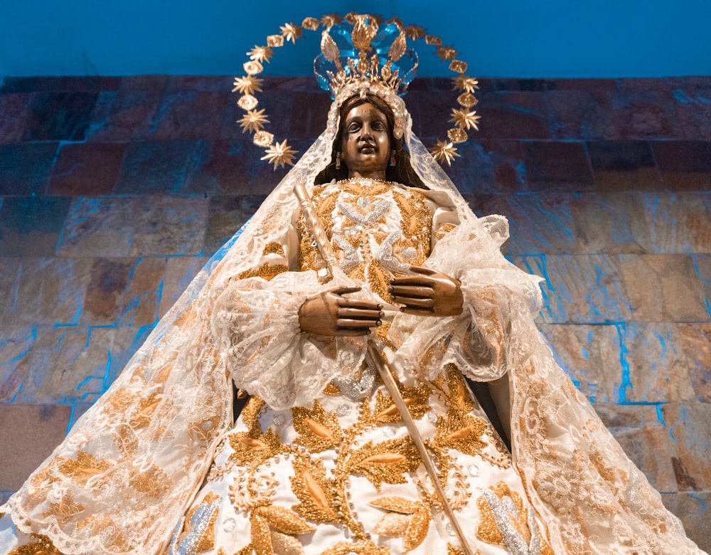 uma estátua de uma mulher em um vestido branco e dourado
