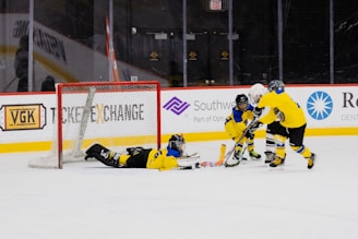 Young hockey players in colorful jerseys competing fiercely on the ice rink under bright arena lights.