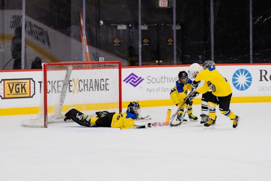Young hockey players in colorful jerseys competing fiercely on the ice rink under bright arena lights.