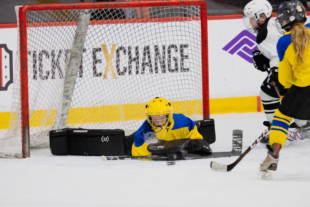 a hockey player laying on the ice in front of a goalie