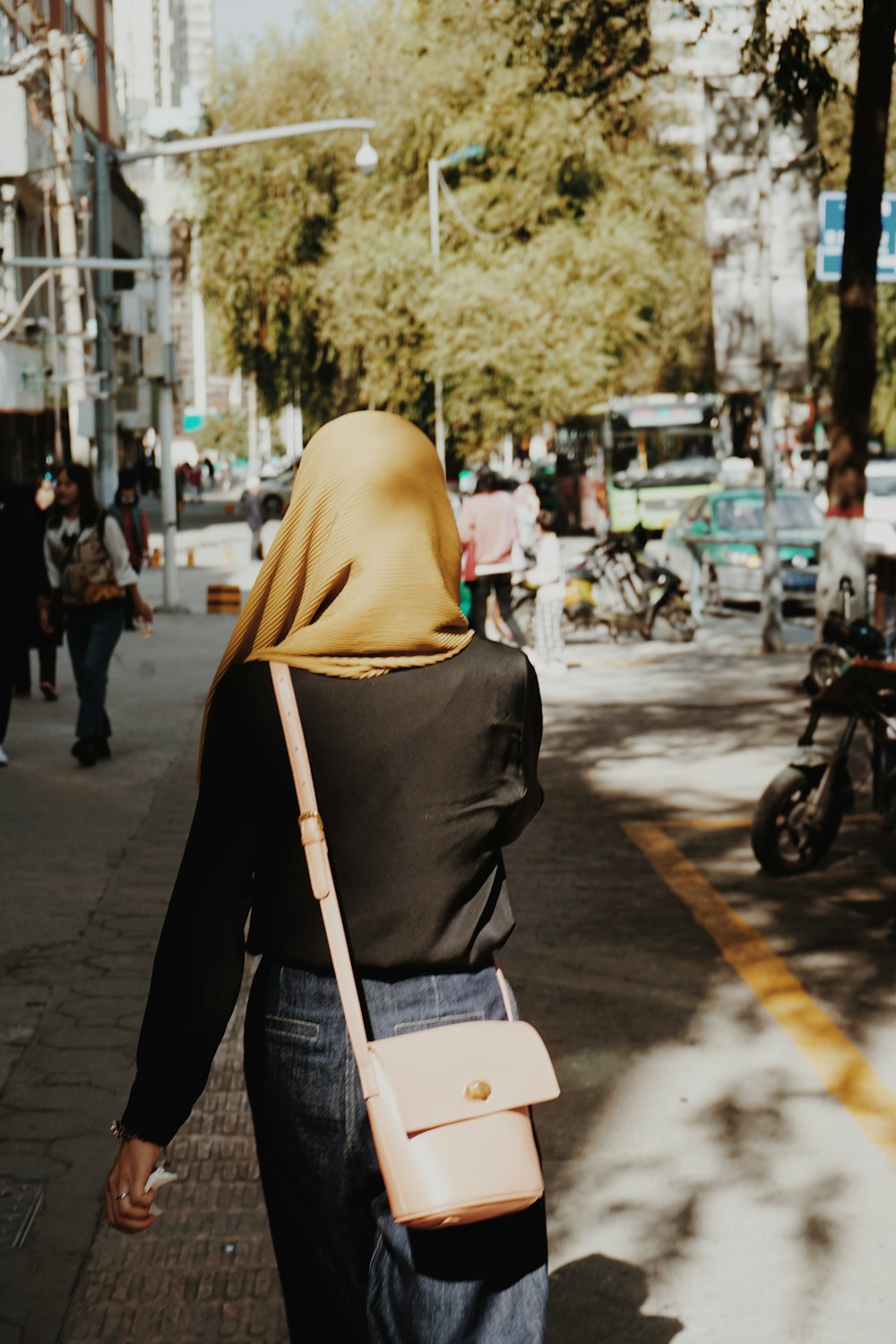 Una mujer caminando por una calle con un bolso rosa