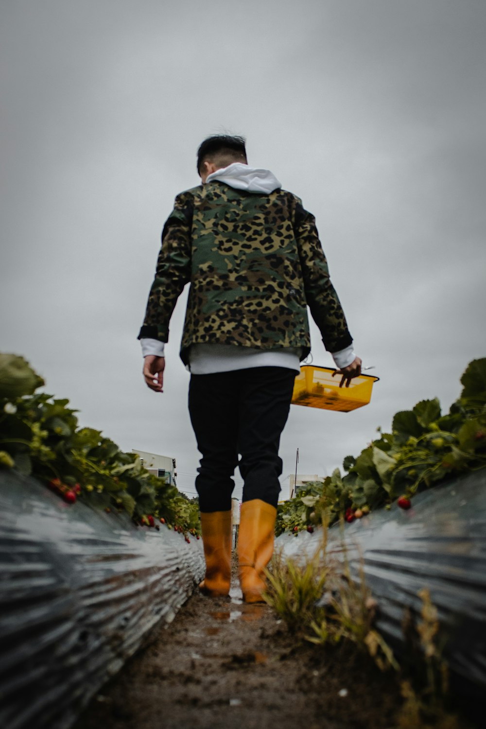 a man in yellow rubber boots is walking through a field