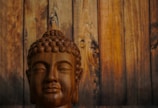 a statue of a buddha in front of a wooden wall