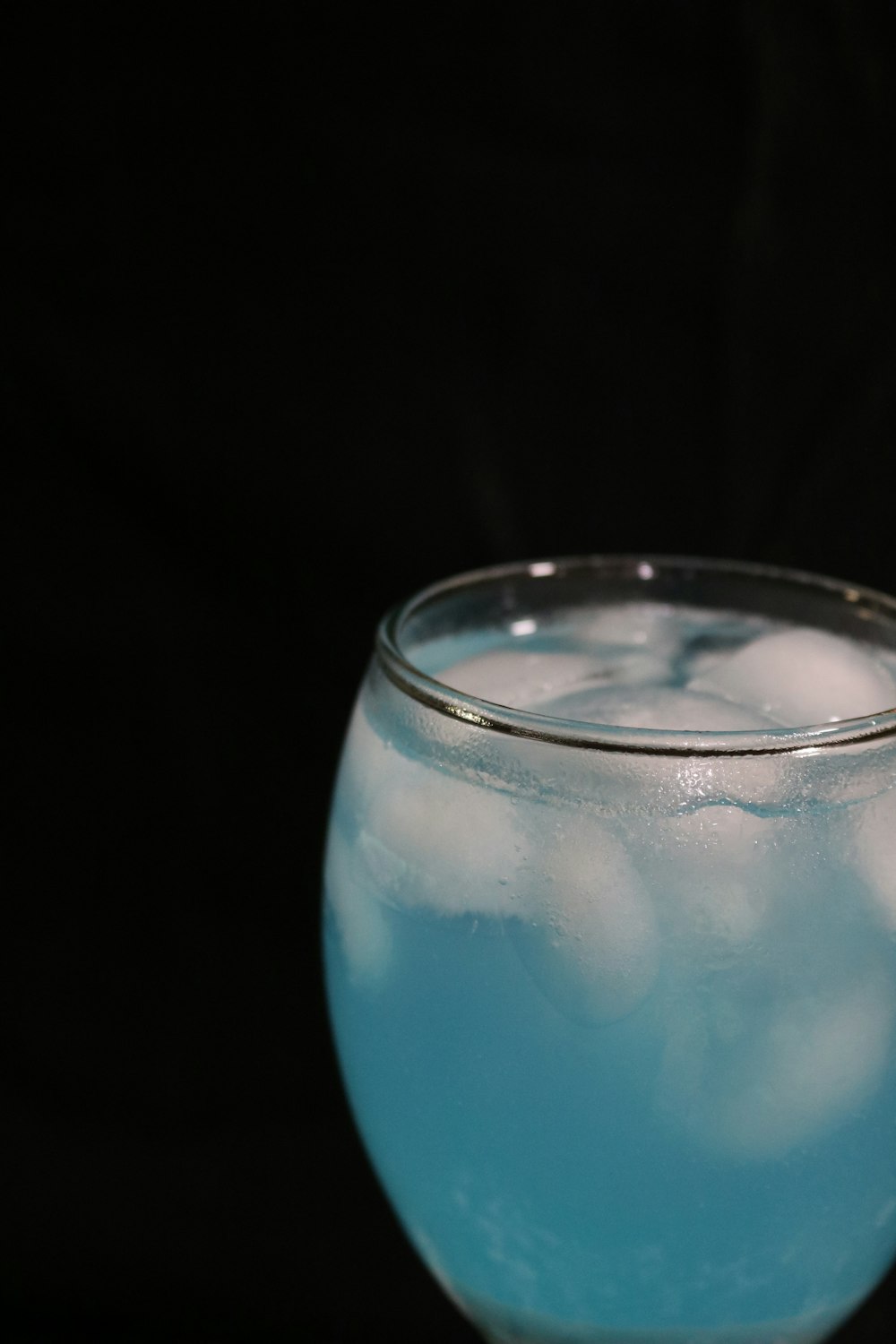 a glass filled with blue liquid on top of a table