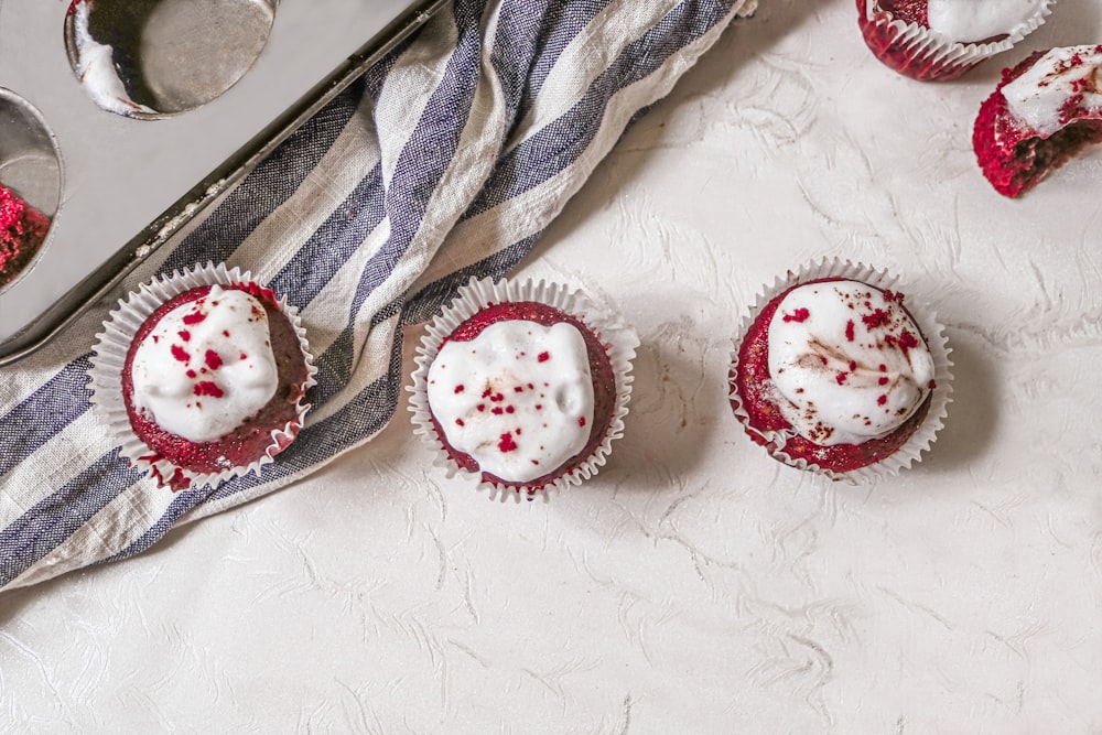 three cupcakes with white frosting and red sprinkles