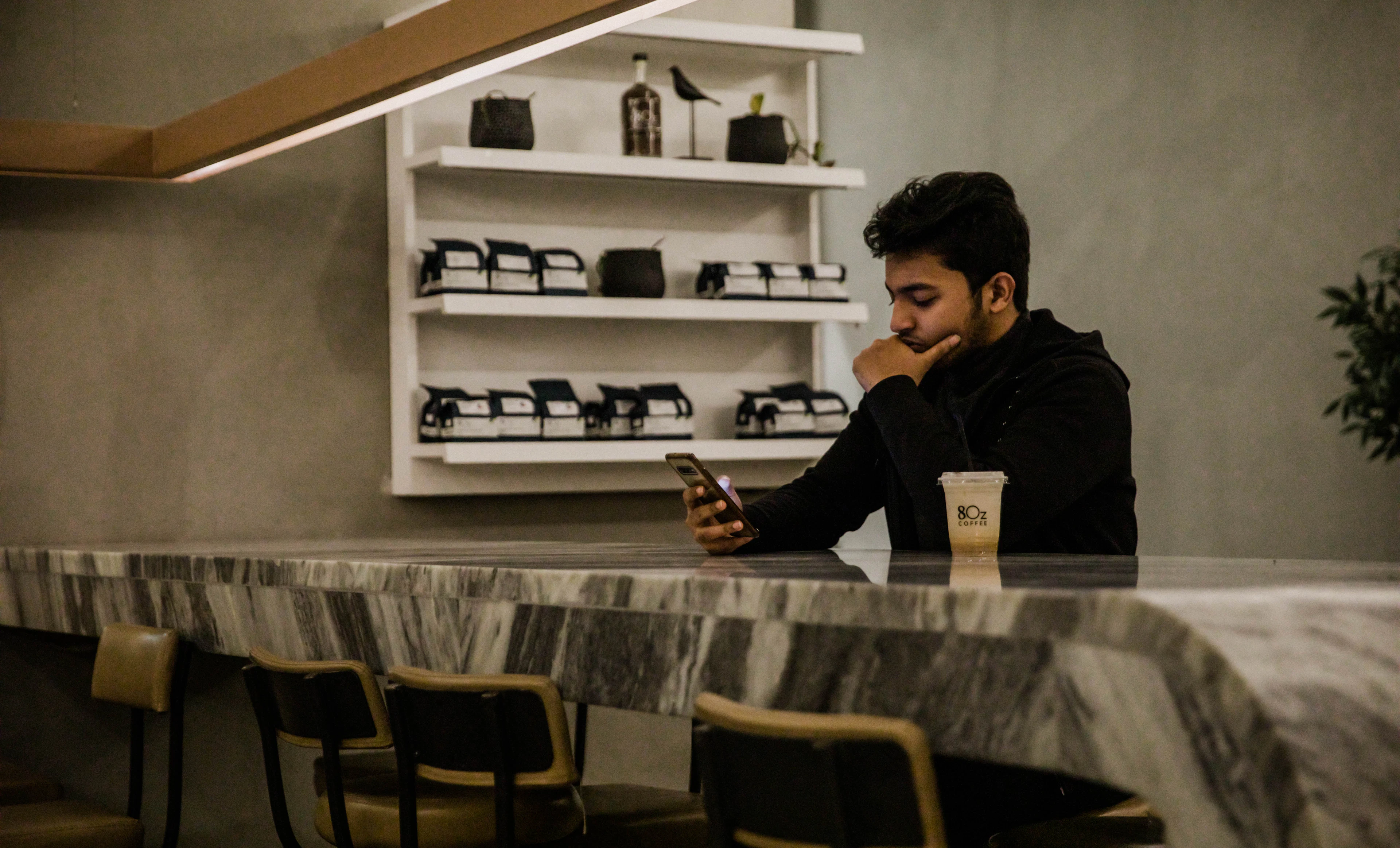 Un homme consulte son téléphone au comptoir d’un café