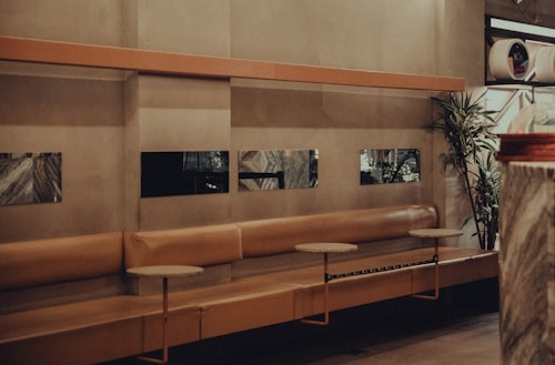 a long bench in a large room with a plant in the corner