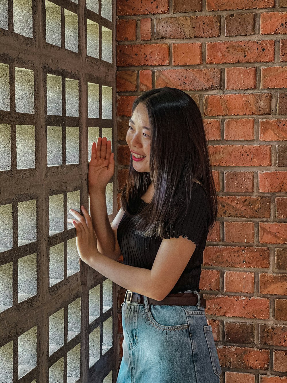 a woman standing next to a brick wall