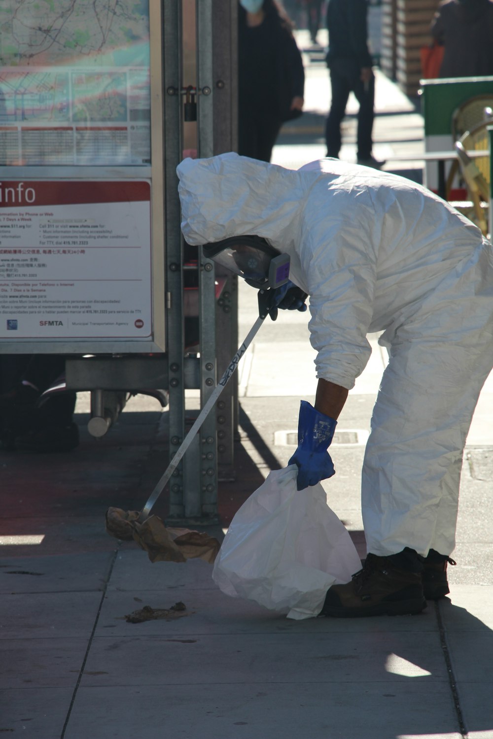 a man in white coveralls cleaning a sidewalk