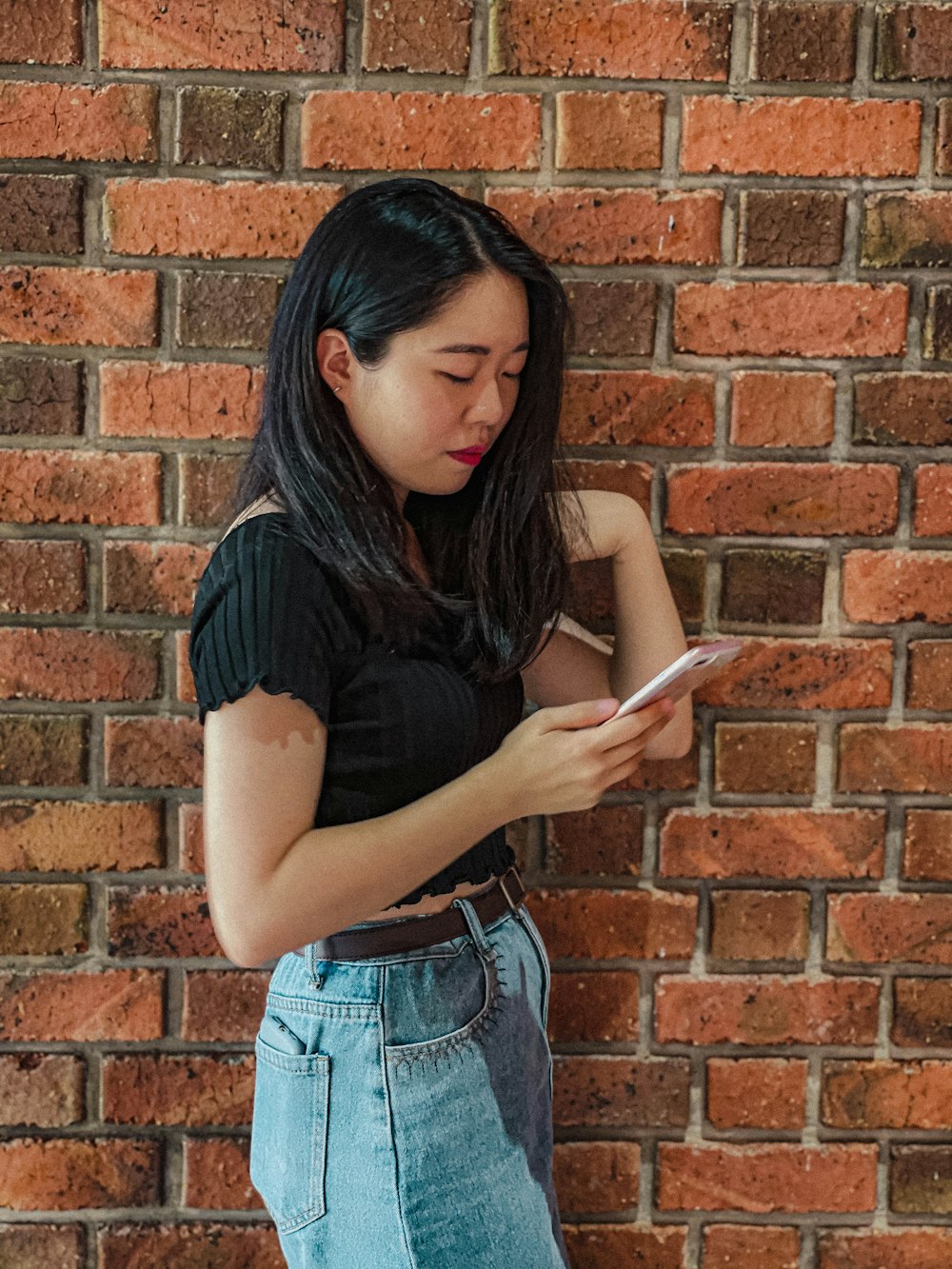 a woman standing next to a brick wall