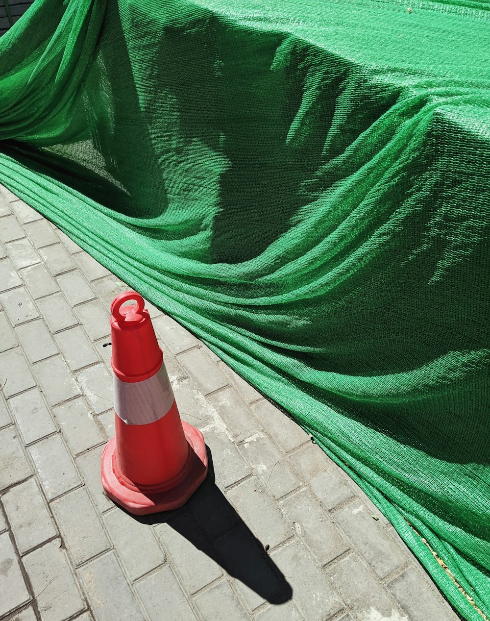 a green tarp covering a fire hydrant on a sidewalk