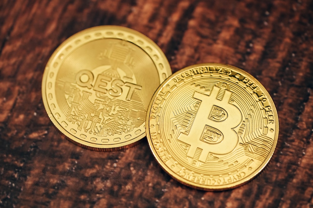 two gold bitcoins sitting on top of a wooden table