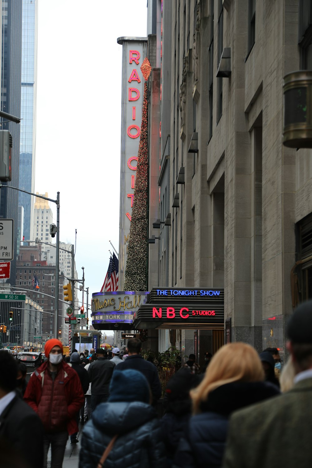 a crowd of people walking down a street next to tall buildings