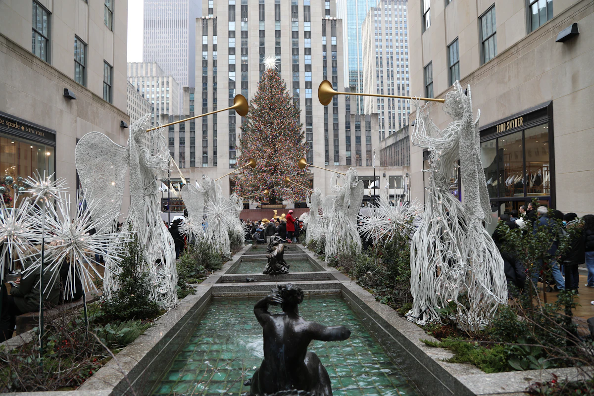 Christmas tree at Rockefeller Center seen along the Channel Gardens with lit angel sculptures