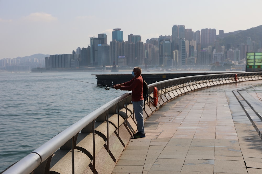 a man standing on a bridge next to a body of water