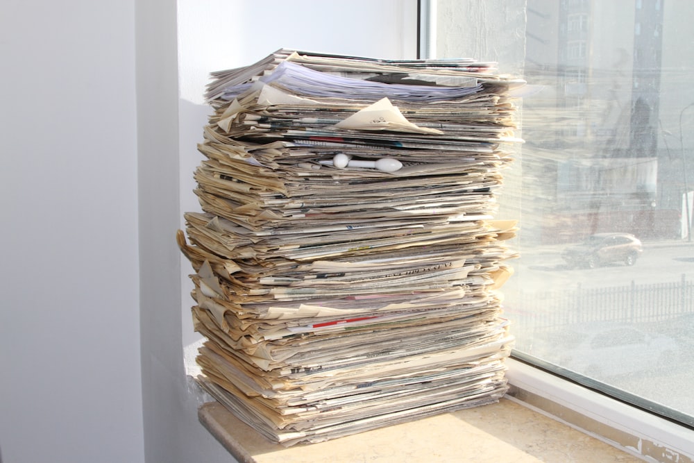 a stack of newspapers sitting on top of a window sill