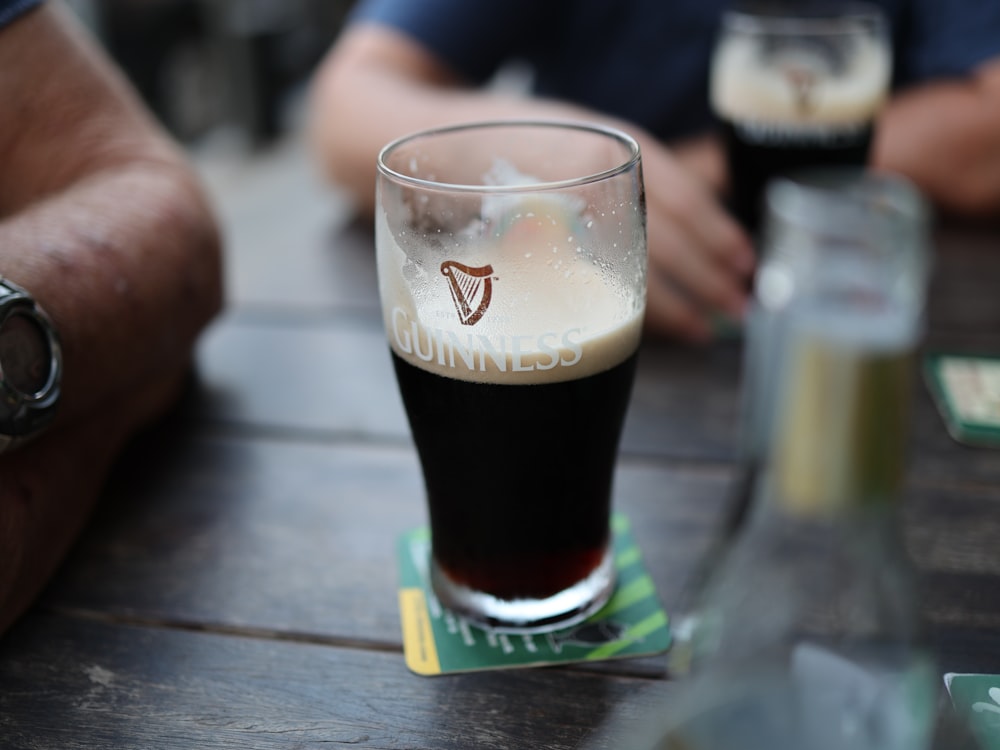 a glass of beer sitting on top of a wooden table