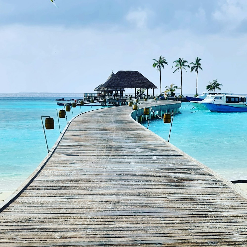 a pier leading to a beach with boats in the water