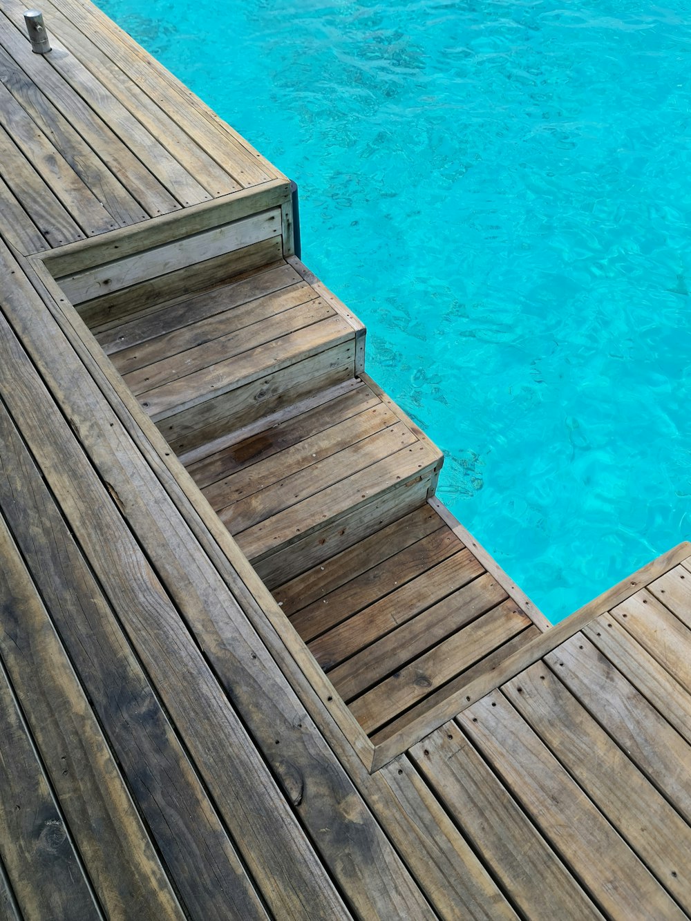 a wooden dock with steps leading to a pool