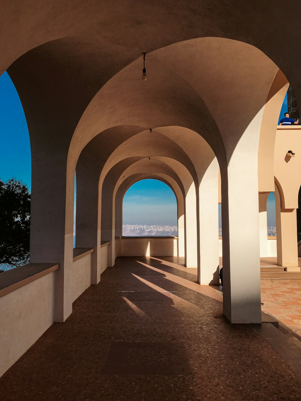 a walkway lined with arches leading to the ocean