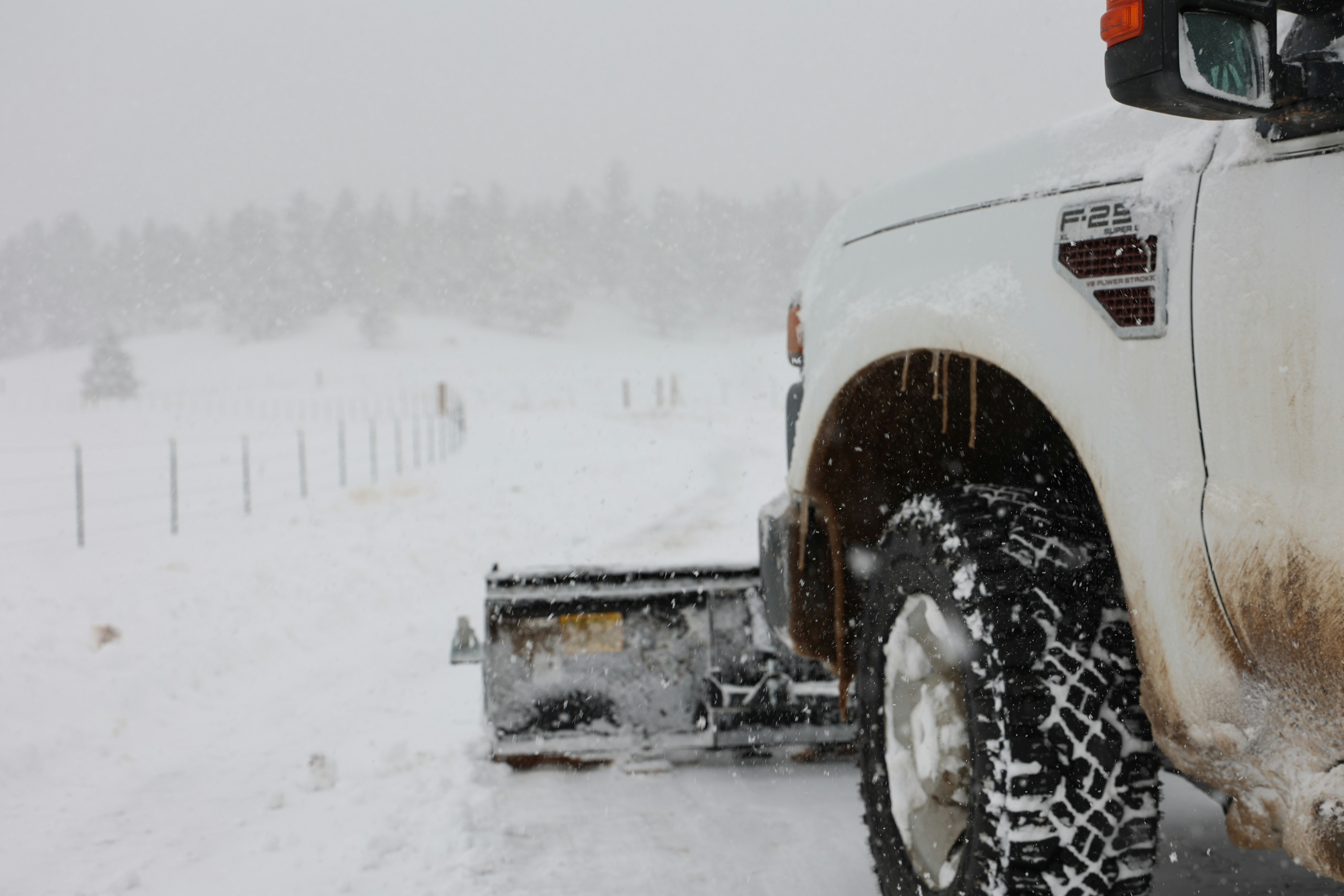 a white truck driving down a snow covered road
