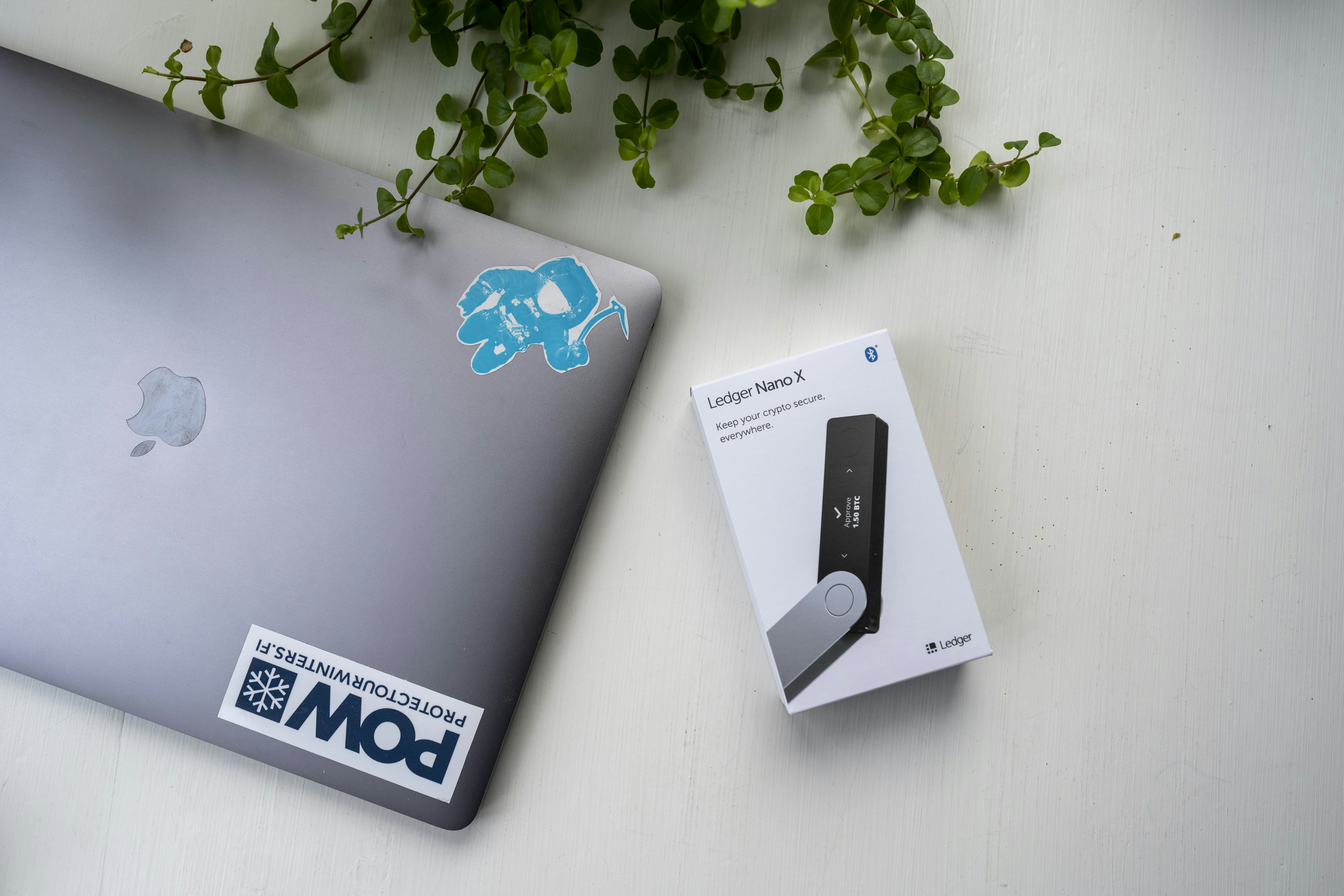 Ledger Nano X hardware wallet next to an MBP.
