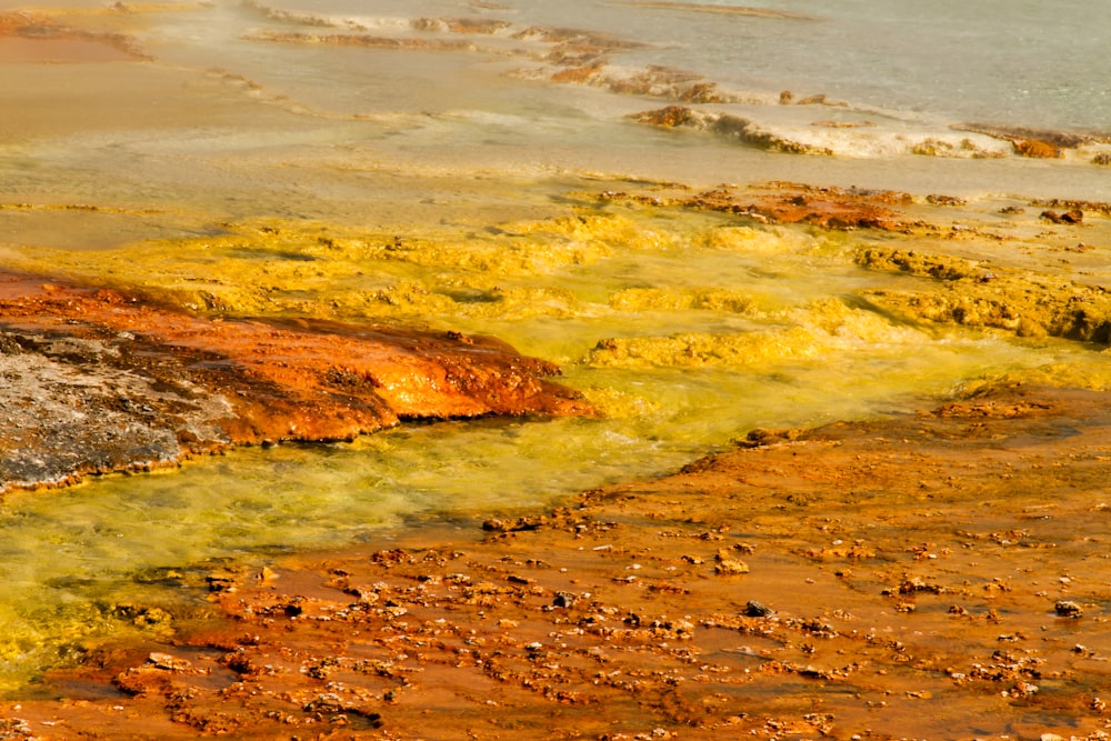 a body of water surrounded by yellow and brown rocks