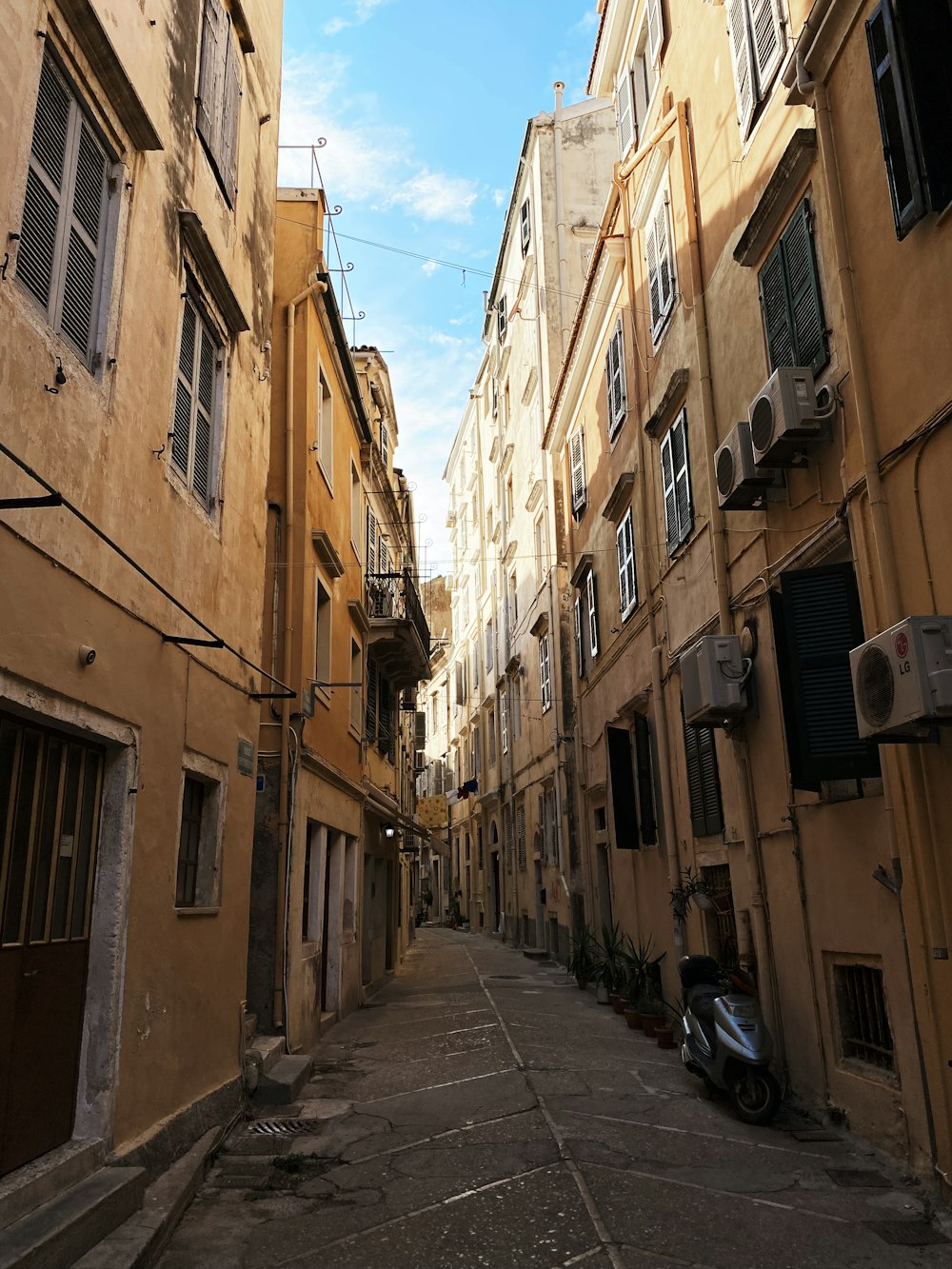 a narrow alley with a scooter parked on the side