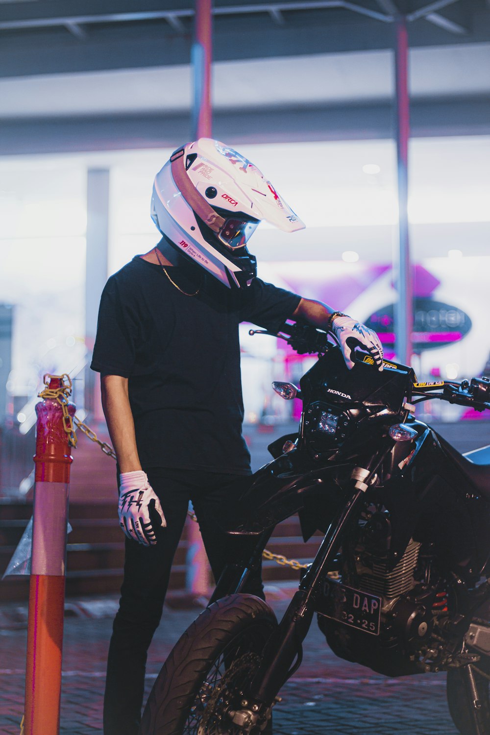 a person wearing a helmet and gloves standing next to a motorcycle