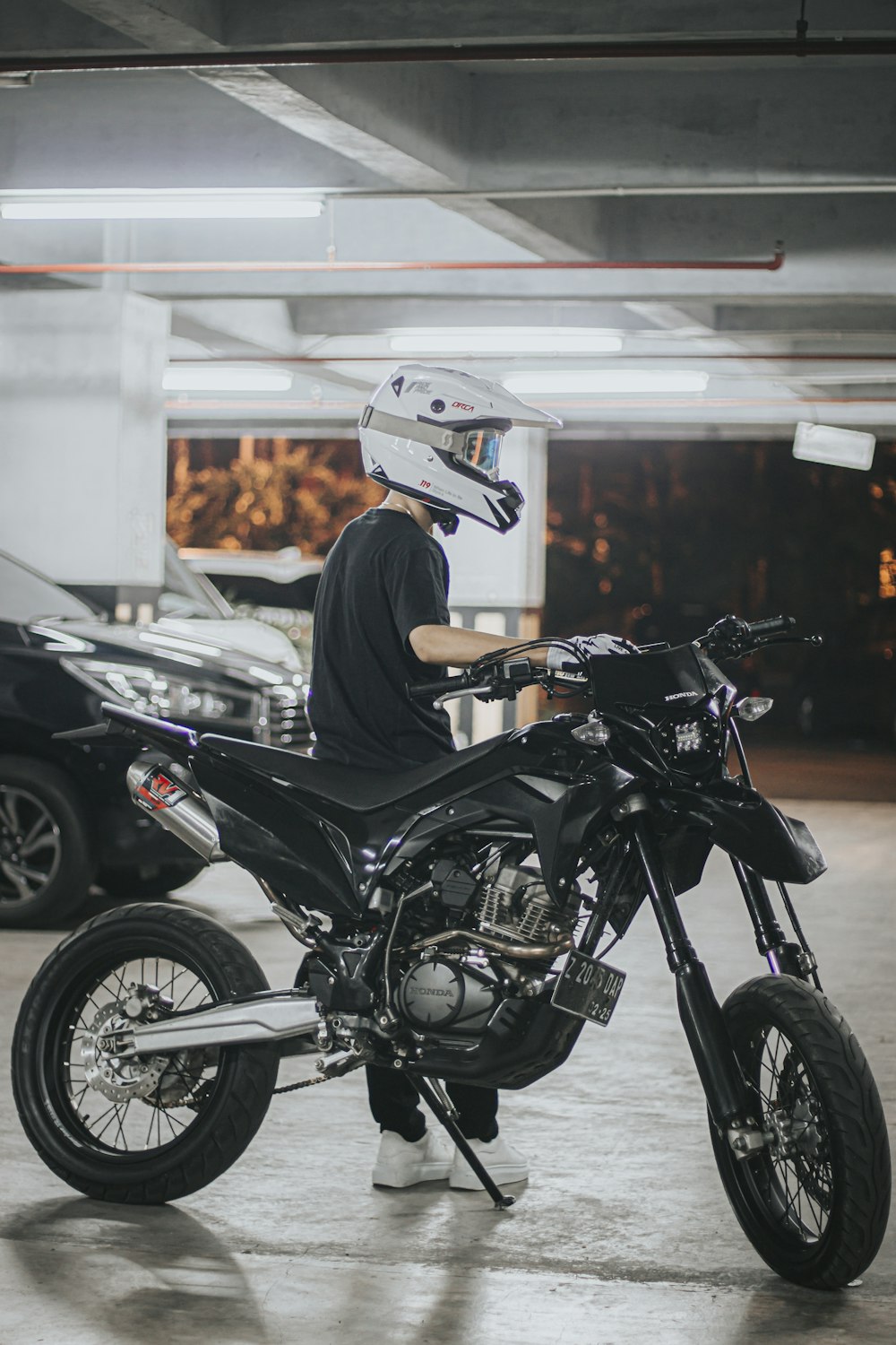 a man sitting on a motorcycle in a parking garage