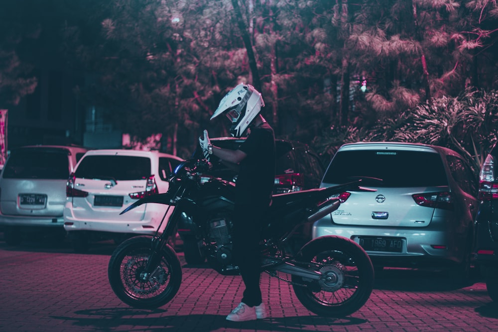 a person sitting on a motorcycle in a parking lot