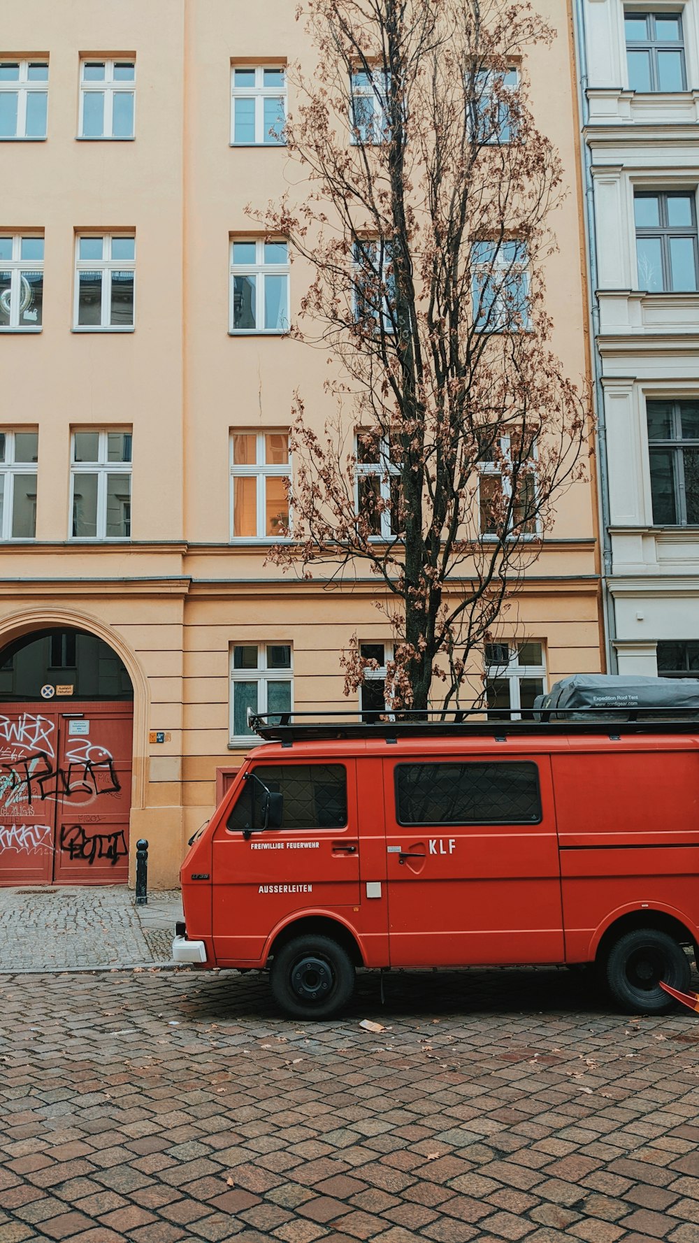 an orange van parked in front of a tall building