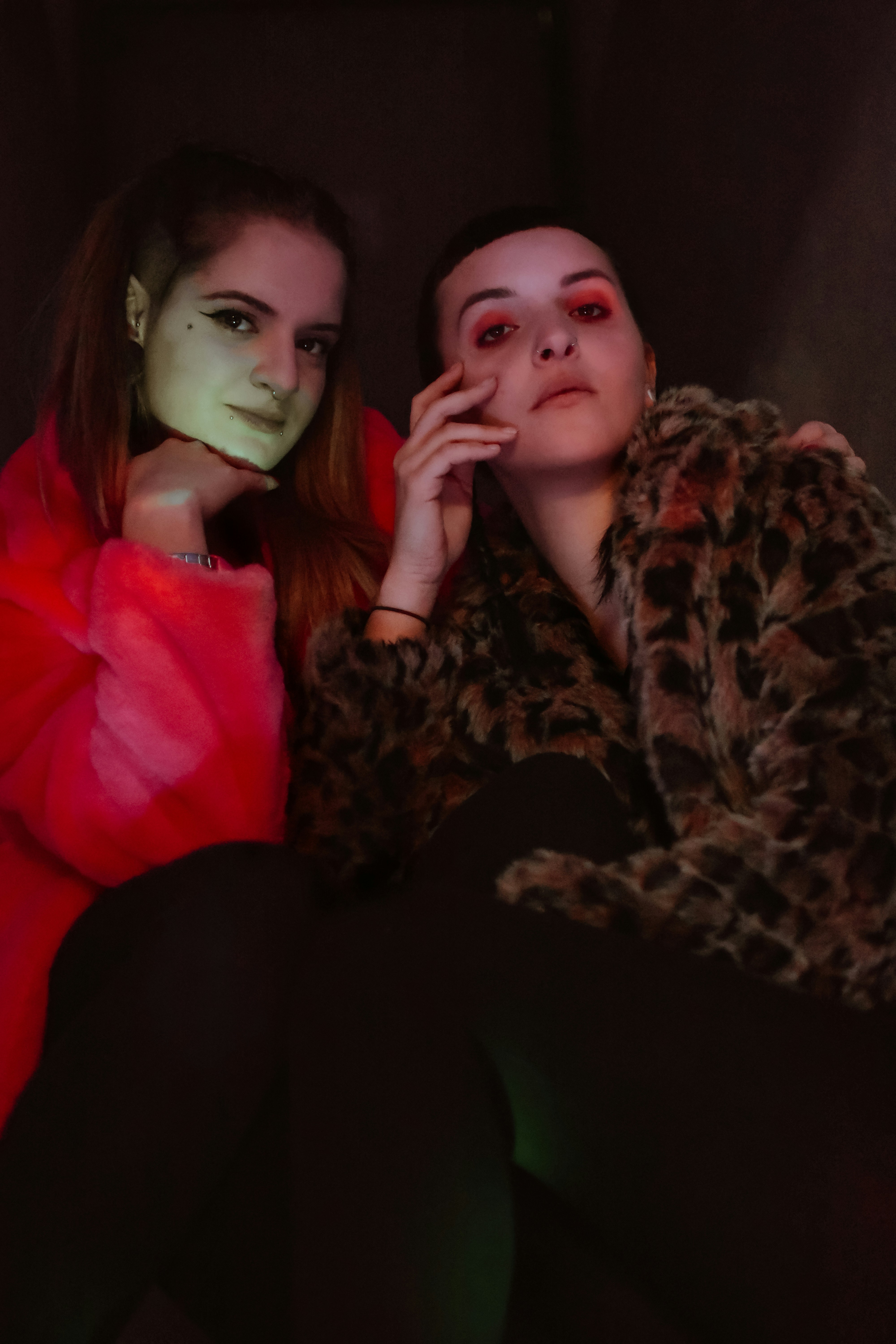 two women sitting next to each other in a dark room
