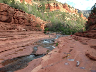 a man standing on the edge of a canyon next to a river