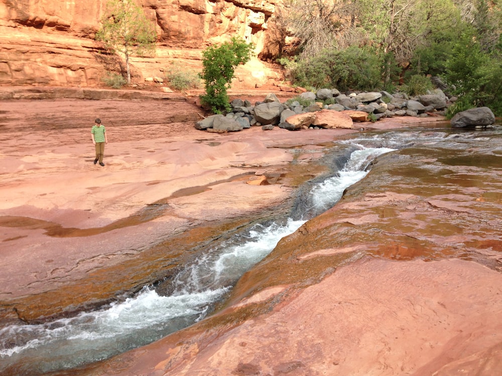 a man standing on a rock next to a river