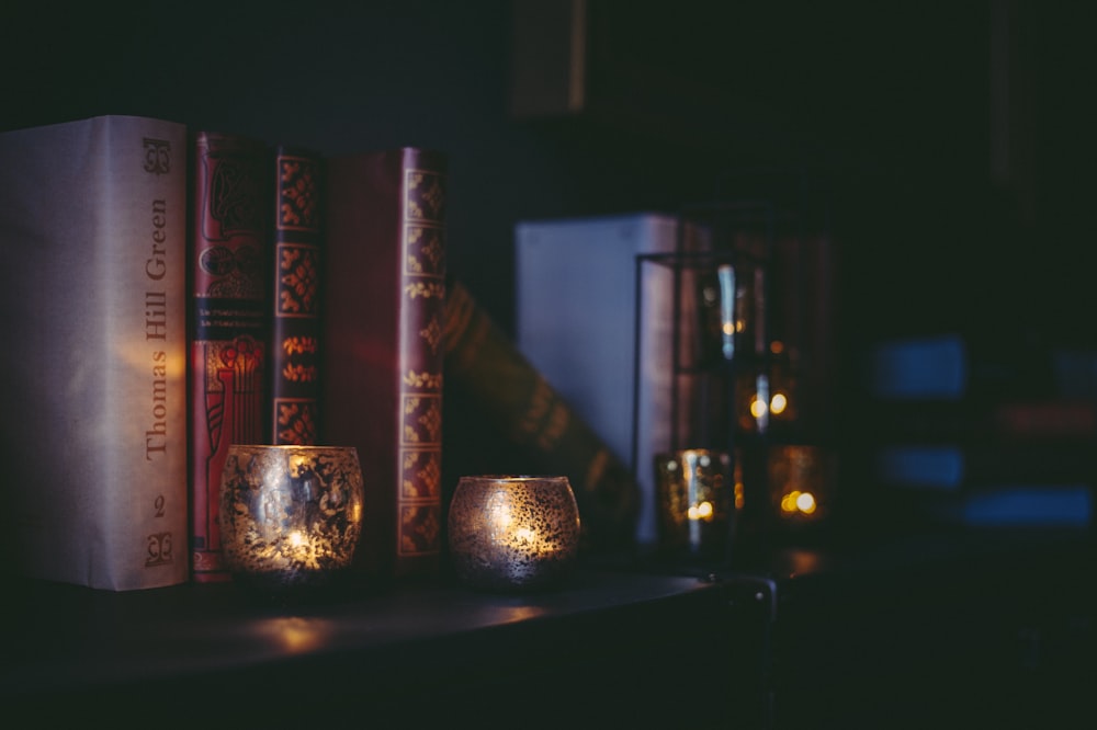 a couple of candles sitting on top of a book shelf