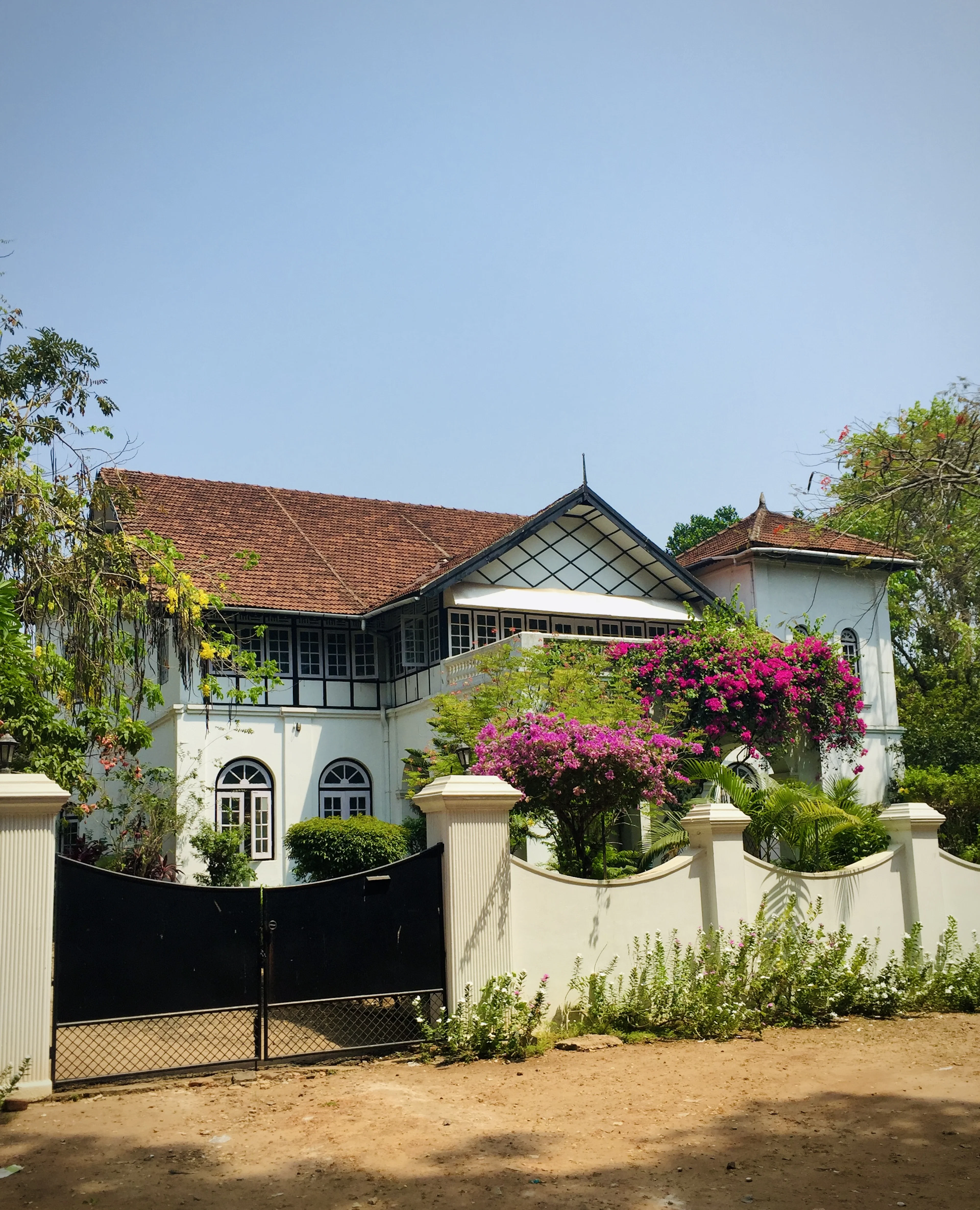 White bungalow behind a black gate with a garden