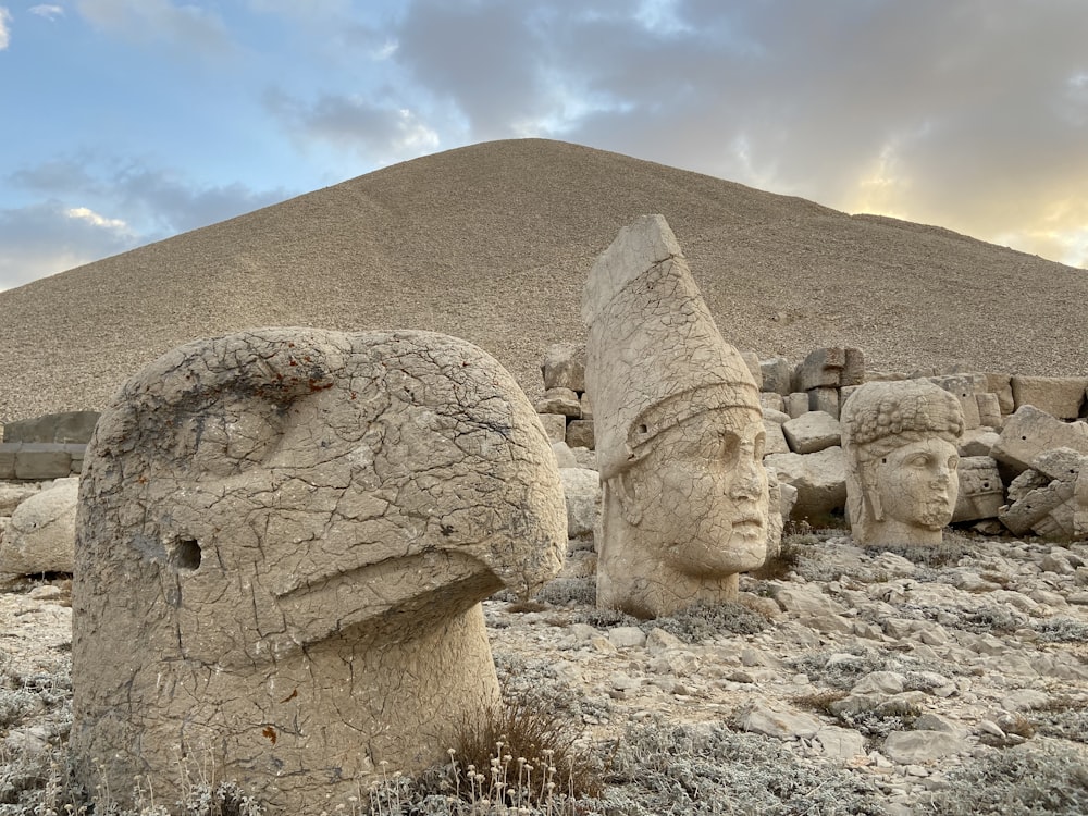 a group of stone statues in front of a pyramid